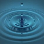 A photograph of a drop of water leaving ripples in a pool.