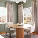 office space with Benjamin Moore storm cloud gray walls, Stefana Silber x Two pages drapes, round wood table with fluted base, light upholstered chairs, Loloii rug, brass and milk glass chandelier