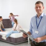 Happy salesman and his clients in mattress store