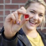 A woman smiling while holding a THC gummy in her hand