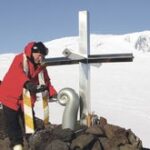 The priest sprinkling sacred water from Aoraki/Mount Cook around the foot of the memorial cross during the Mount Erebus memorial service.