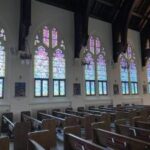 Jordan Bennett | Saint Mary’s College standing in front of a stained glass window depicting biblical figures, illustrating the scholarly approach to biblical studies and interpretation.