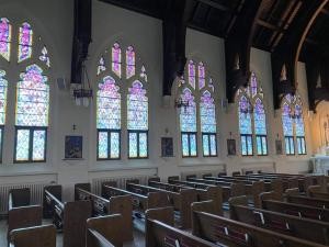 Jordan Bennett | Saint Mary’s College standing in front of a stained glass window depicting biblical figures, illustrating the scholarly approach to biblical studies and interpretation.