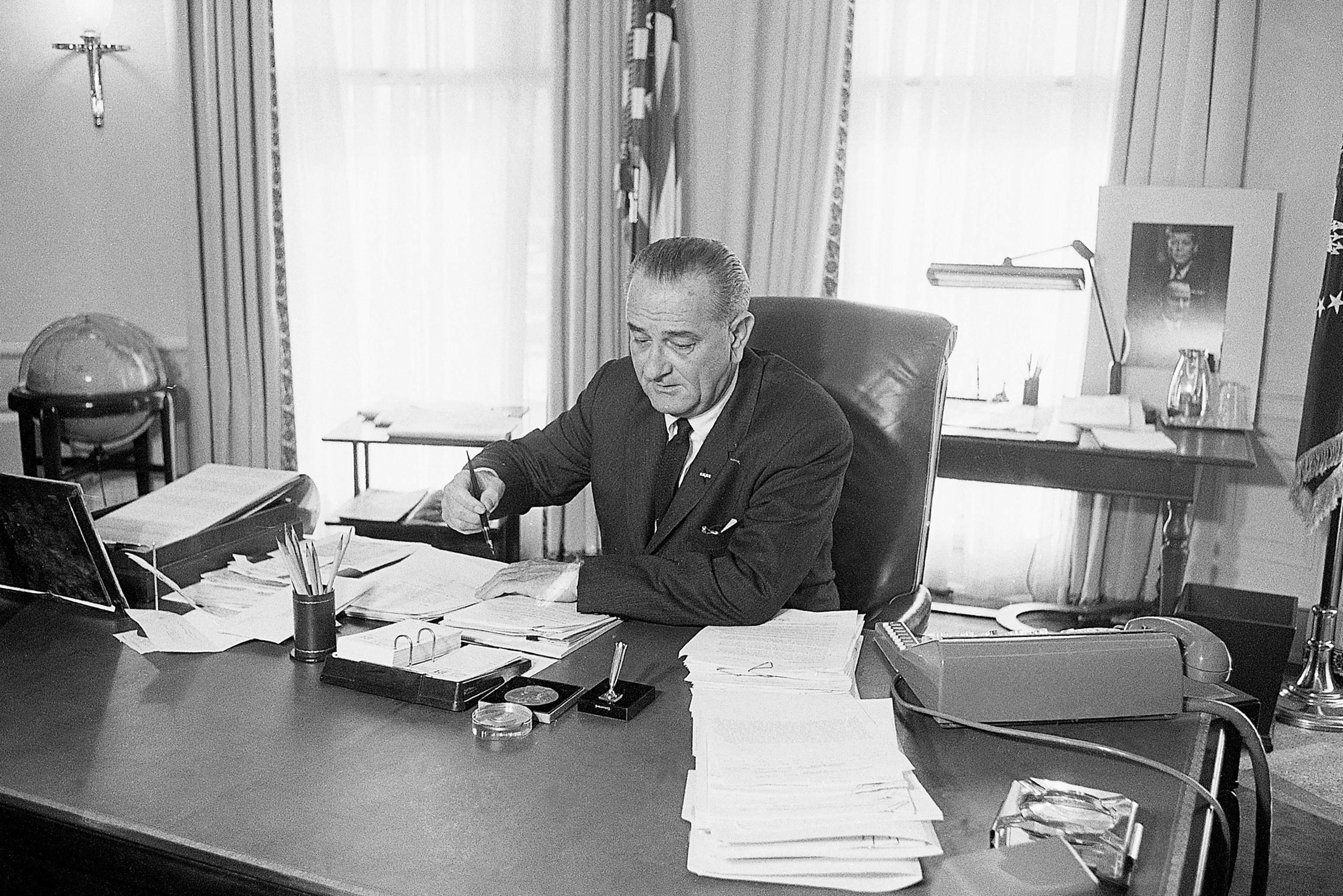 President Lyndon B. Johnson in the Oval Office, 1965, reflecting on critical decisions, a moment relevant when comparing LBJ and Biden's presidencies.