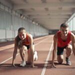 Male and female athletes running on track