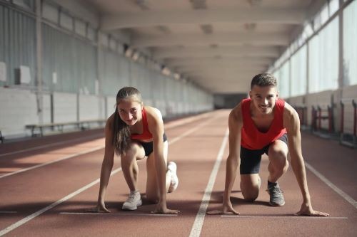 Male and female athletes running on track