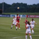 six woman playing soccer on soccerfield