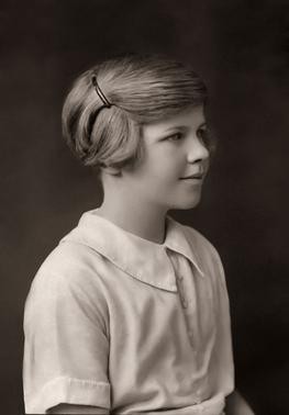 Black and white photo of a young girl with a spiral bun in her hair. Venetia Burney, the eleven-year-old girl who named Pluto, in a vintage portrait.