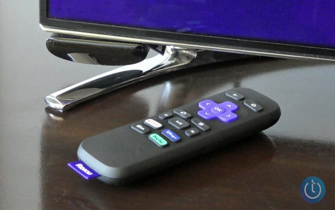 Roku Express attached to TV with remote control on the console