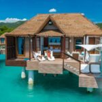 Overwater bungalows at Sandals South Coast resort in Jamaica, offering luxurious accommodations directly above the turquoise Caribbean Sea.