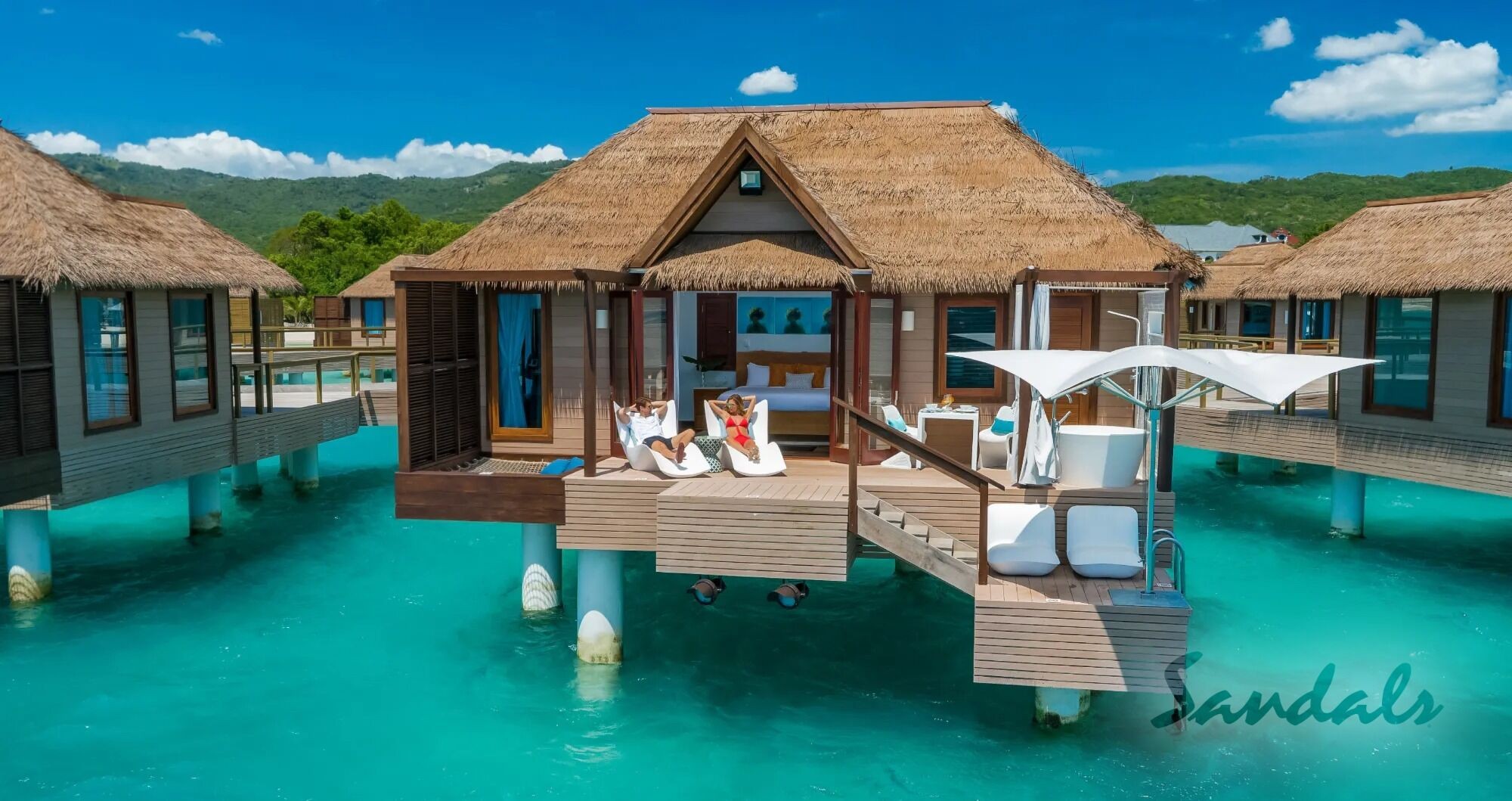 Overwater bungalows at Sandals South Coast resort in Jamaica, offering luxurious accommodations directly above the turquoise Caribbean Sea.