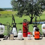 Eight pump sprayers lined up on a lawn