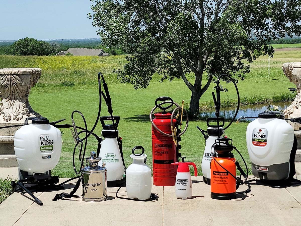 Eight pump sprayers lined up on a lawn