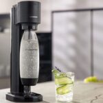 SodaStream Gaia on a countertop with a glass of sparkling water infused with cucumber