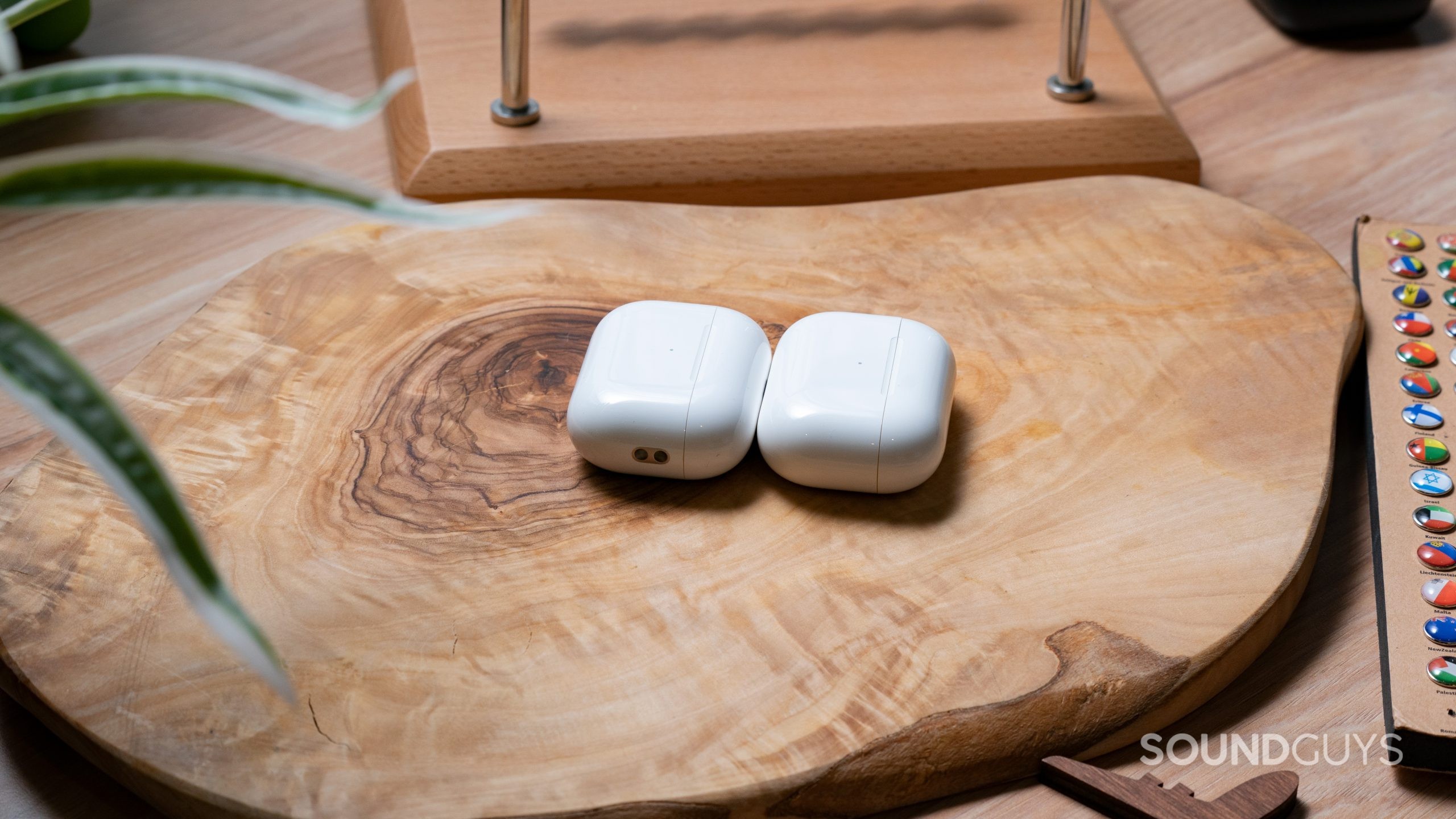 The Apple AirPods Pro (2nd generation) Case Lays on a Wooden Surface Next to the Apple AirPods Pro (1st generation) Case
