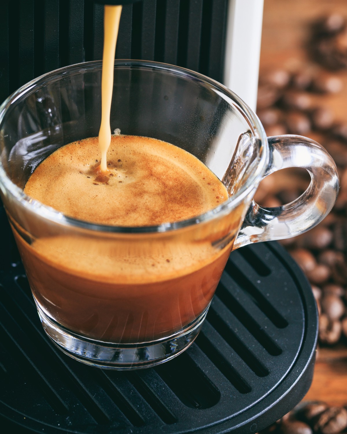 Close up of espresso pouring from a machine, highlighting rich color and crema