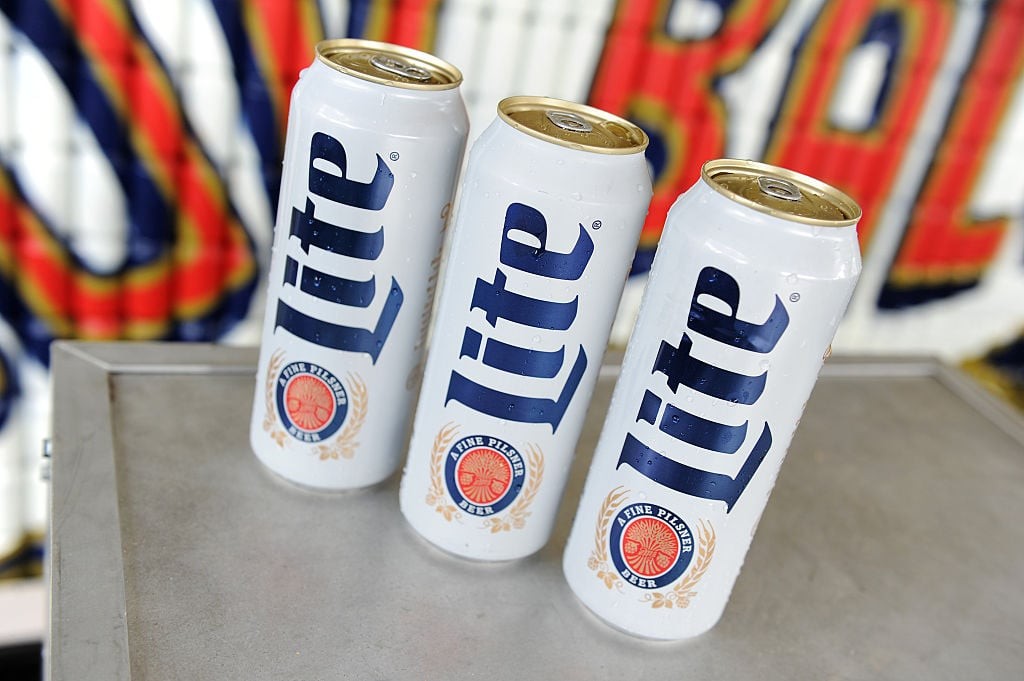Two cans of Miller Lite are arranged on a dark surface, emphasizing their classic design and silver color