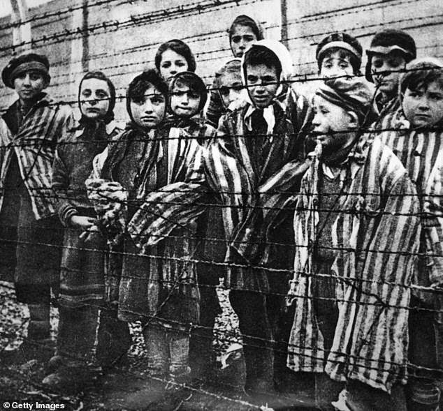 A group of child survivors behind a barbed wire fence at the Nazi concentration camp at Auschwitz-Birkenau in southern Poland, on the day of the camp