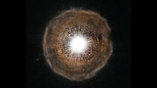 A bright white sphere at the center is surrounded by brownish hazy shell against the black backdrop of space