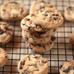 Many chocolate chip cookies on a cooling rack.
