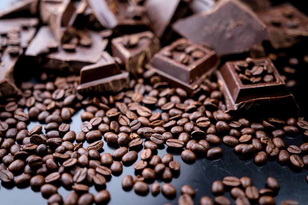 Dark organic chocolate and coffee beans on concrete background