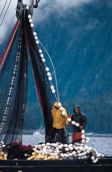 Fishermen on a boat using a pulley to pull in their net, illustrating a real-world application where a pulley system provides a mechanical advantage and changes the direction of force, making it easier to haul heavy loads.
