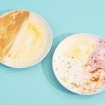 Two white plates smeared with different foods and sauces.
