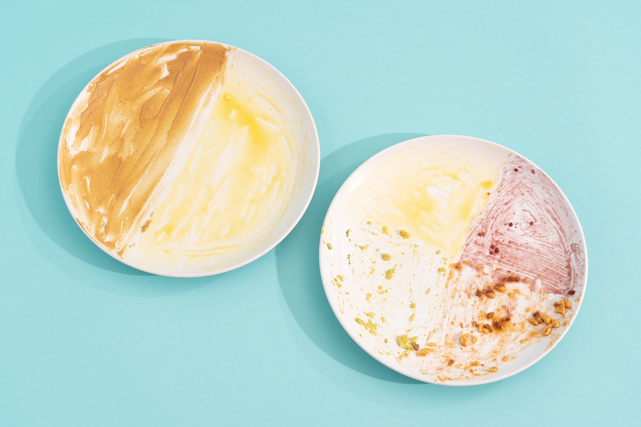 Two white plates smeared with different foods and sauces.