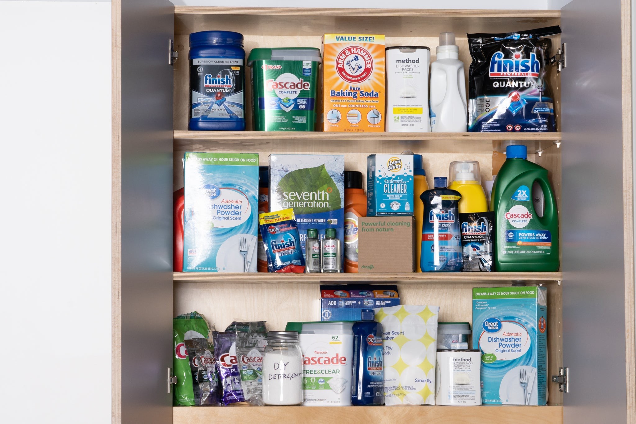 Three shelves with various dishwashing powders, detergents, powders and baking sodas sitting on them.