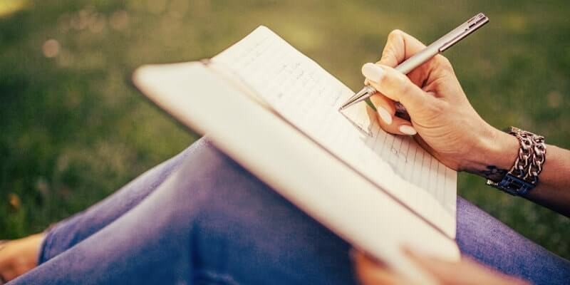 Woman writing in a gratitude journal, overcoming comparison.