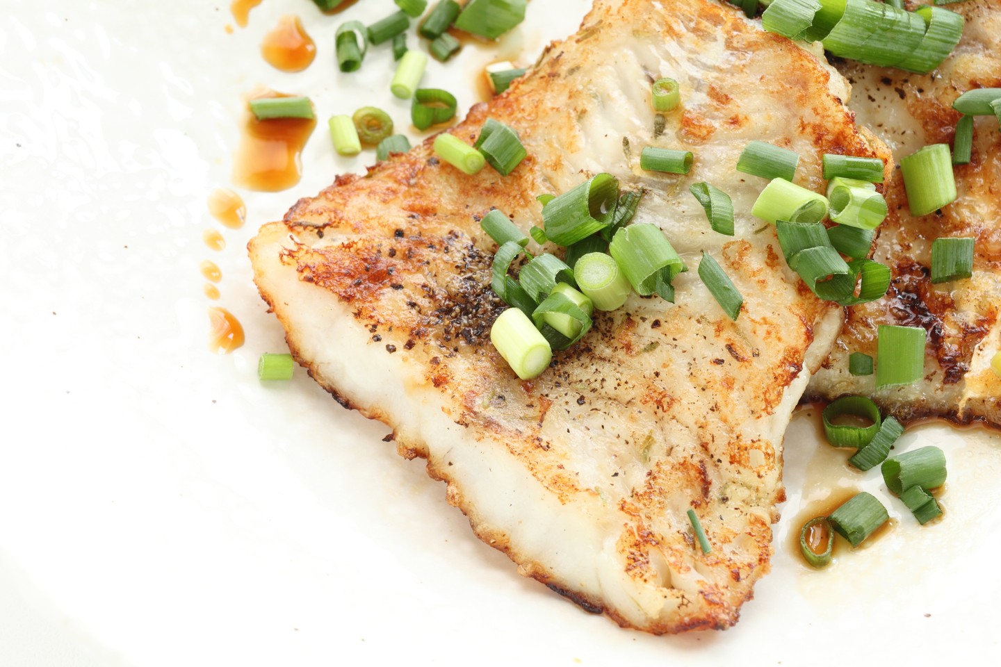 A photo of a Pacific Cod fillet with scallions on top