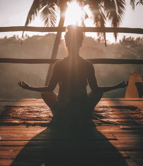 Woman practicing self-compassion by meditating in nature