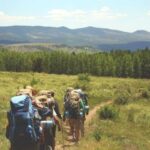 People hiking in mountainous countryside with large backpacks