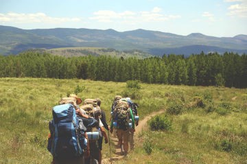 People hiking in mountainous countryside with large backpacks